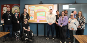 NHS staff and students/staff from The Grimsby Institute in front of a screen showing a video game