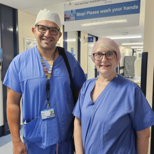 Man and woman wearing surgical scrubs in a ward environment 