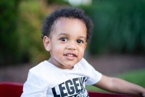 Little boy wearing a white "Legend" t-shirt smiles at the camera