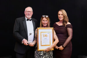 a woman stood with a gold framed certificate 