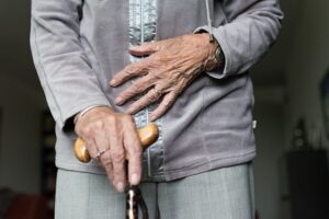 Older woman holds a walking stick in one hand