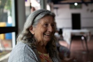 Older woman with grey hair held back by a hairband smiles at the camera