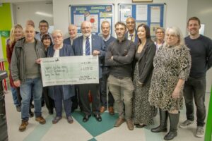 Mrs Knowles holds her giant cheque surrounded by her friends and members of staff from Ward 40