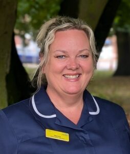 Donna Gotts smiles for the camera wearing her uniform and staff badge